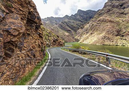 Stock Image - "Road at the Embalse Presa del Parralillo reservoir, also called """"the green lake"""", in the mountains of Caldera de Tejeda, also called a """"petrified storm"""", Artenara Region, Gran Canaria, Canary Islands, Spain, Europe, PublicGround, Europe". Fotosearch