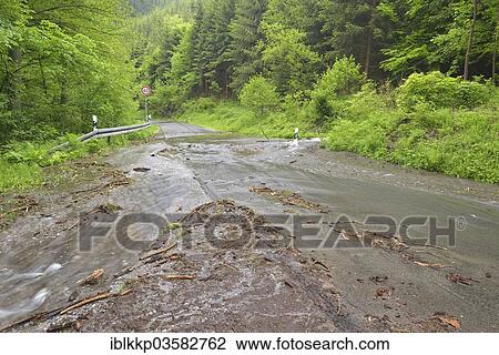 Stock Image - "Road in the Harz region covered in water and debris after heavy rainfalls, Thale, Saxony-Anhalt, Germany, Europe". Fotosearch