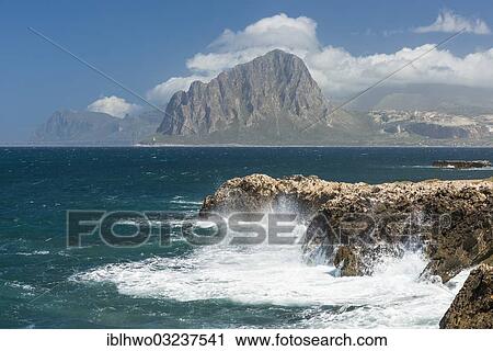 Stock Image - "Rocky coast with waves, Monte Cofano Nature Reserve at back, Pizzolungo, Nordwest-Kuste, Nordwest-Kuste, Provinz Trapani, Sicily, Italy, Europe". Fotosearch