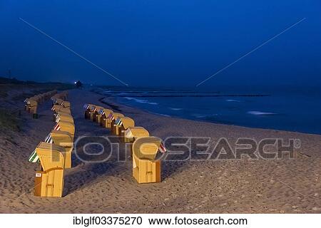 Stock Image - "Roofed wicker beach chairs on a beach on the Baltic Sea coast at night, Wustrow, Mecklenburg-Western Pomerania, Germany, Europe". Fotosearch