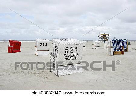 Stock Photo - "Roofed wicker beach chairs on the beach in front of a house on stilts, St Peter-Ording, Schleswig-Holstein, Germany, Europe". Fotosearch