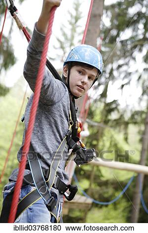 Stock Image - "Roped up boy climbing in a climbing park, Karlovy Vary Region, Bohemia, Czech Republic, Europe". Fotosearch