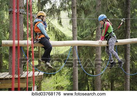 Stock Photograph - "Roped up girls climbing in a climbing park, Karlovy Vary Region, Bohemia, Czech Republic, Europe". Fotosearch