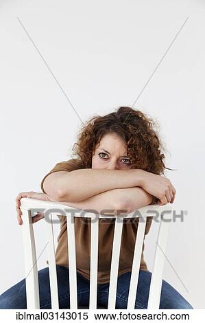 Stock Photography - Sad young woman sitting on a chair. Fotosearch