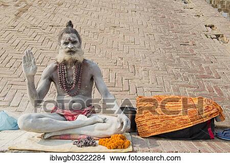 Picture - "Sadhu, holy man or wandering ascetic sitting in the lotus position on a cloth, his body is smeared with white ashes in the sign of Shiva, Varanasi, Uttar Pradesh, India, Asia". Fotosearch