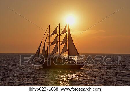 Stock Photo - "Sailing ship at sunset near Oia, Santorini, Cyclades, Greek island, Greece, Europe". Fotosearch