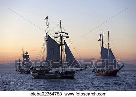 Stock Photo - "Sailing ships against an atmospheric evening sky, Hanse Sail 2012, Warnemuende, Mecklenburg-Western Pomerania, Germany, Europe". Fotosearch