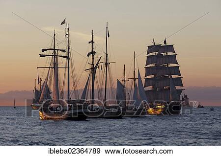 Stock Photo - "Sailing ships against an atmospheric evening sky, Hanse Sail 2012, Warnemuende, Mecklenburg-Western Pomerania, Germany, Europe". Fotosearch