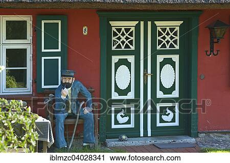 Stock Image - "Sailor figure, bank at an entrance door, thatched cottage, Ahrenshoop, Darss, Fischland-Darss-Zingst, Mecklenburg-Western Pomerania, Germany, Europe". Fotosearch