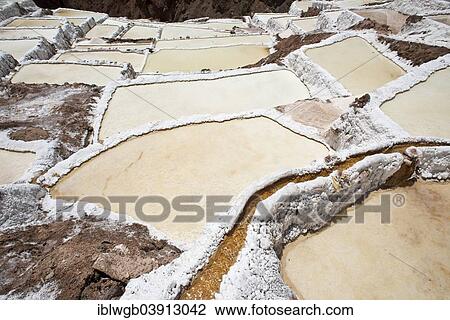 Stock Image - "Salt pans with water course on a mountainside, Salinas de Maras salt pans, created by the Incas and still in operation, Pichingote, Cusco region, Andes, Peru, South America". Fotosearch