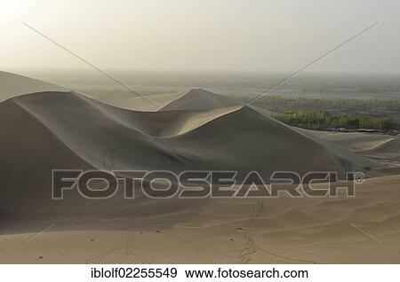 Stock Photo - "Sand dunes with a caravan trail in the Gobi Desert in front of the green oasis of Dunhuang, Silk Road, Dunhuang, Gansu, China, Asia". Fotosearch