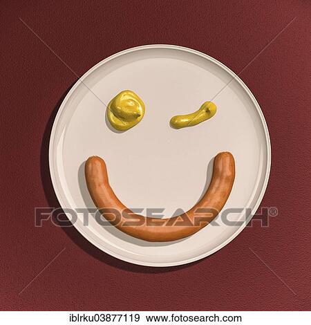 Stock Photo - "Sausage and drops of mustard, winking smiley face on a plate". Fotosearch