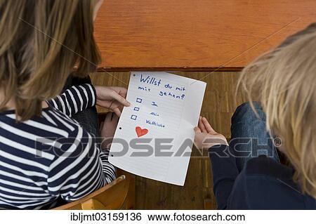 Stock Photograph - "School children secretly passing notes under the school desk, Germany, Europe". Fotosearch