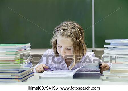 "Schoolgirl, 7 years, reading a book whilst sitting between two stacks of books, in front of a blackboard" View Large Photo Image Stock Photography - "Schoolgirl, 7 years, reading a book whilst sitting between two stacks of books, in front of a blackboard". Fotosearch