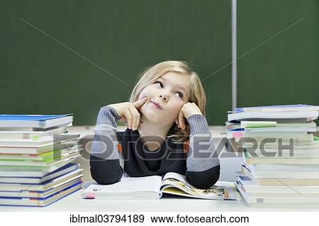 "Schoolgirl, 9 years, looking pensive, sitting between two piles of books in front of a blackboard" View Large Photo Image Stock Photo - "Schoolgirl, 9 years, looking pensive, sitting between two piles of books in front of a blackboard". Fotosearch