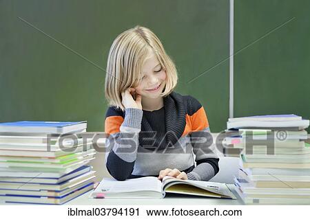 "Schoolgirl, 9 years, reading a book whilst sitting between two stacks of books, in front of a blackboard" View Large Photo Image Stock Image - "Schoolgirl, 9 years, reading a book whilst sitting between two stacks of books, in front of a blackboard". Fotosearch