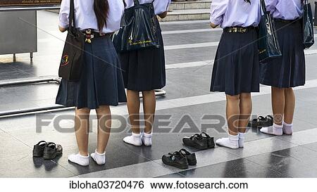 Stock Photograph - "Schoolgirls standing in front of a shrine with their shoes taken off, Bangkok, Central Thailand, Thailand, Asia". Fotosearch