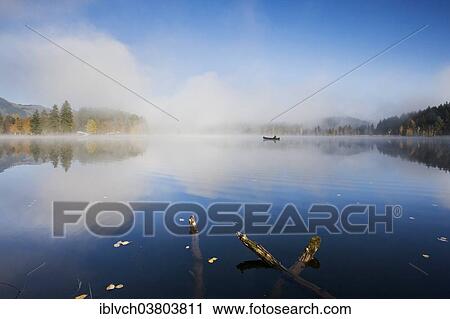 Stock Image - "Schwarzsee with fishing boat in the morning mist, Kitzbuehel, Tyrol, Austria, Europe". Fotosearch