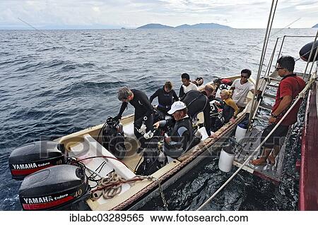 Stock Photography - "Scuba divers boarding the diving dinghy, Buginese Schooner, Seven Seas Liveaboard, Dampier Strait, West Papua, Indonesia, Asia". Fotosearch