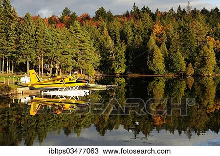 Stock Image - "Seaplane on Smoke Lake, in front of a log house in the autumn-coloured forest, Algonquin Provincial Park, Ontario Province, Canada, North America". Fotosearch