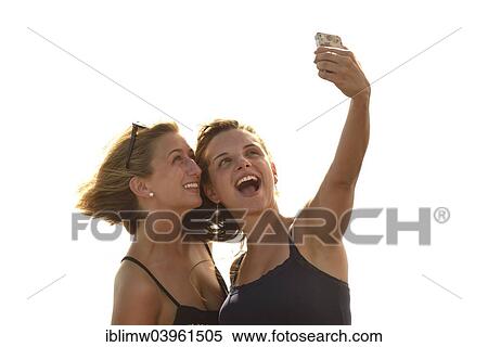 Stock Photography - "Selfie, two young women taking a self-portrait with a mobile phone, Lanzarote, Canary Islands, Spain, Europe". Fotosearch