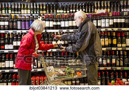 Stock Image - "Senior couple shopping in the wine department in a supermarket, Germany, Europe". Fotosearch
