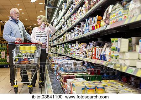 "Senior couple shopping with a shopping trolley in the refrigerated dairy section in a supermarket, Germany, Europe" View Large Photo Image Stock Image - "Senior couple shopping with a shopping trolley in the refrigerated dairy section in a supermarket, Germany, Europe". Fotosearch