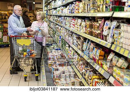 "Senior couple shopping with a shopping trolley in the refrigerated dairy section in a supermarket, Germany, Europe" View Large Photo Image Stock Photo - "Senior couple shopping with a shopping trolley in the refrigerated dairy section in a supermarket, Germany, Europe". Fotosearch