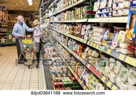 Stock Photo - "Senior couple shopping with a shopping trolley in the refrigerated dairy section in a supermarket, Germany, Europe". Fotosearch
