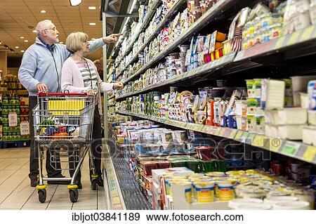 "Senior couple shopping with a shopping trolley in the refrigerated dairy section in a supermarket, Germany, Europe" View Large Photo Image Stock Photo - "Senior couple shopping with a shopping trolley in the refrigerated dairy section in a supermarket, Germany, Europe". Fotosearch