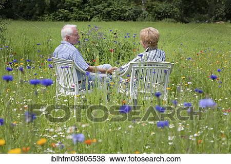 Stock Photo - "Senior couple sitting on a meadow, Lower Saxony, Germany, Europe". Fotosearch