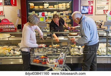 "Senior couple with a shopping trolley, shopping at the cheese counter of a supermarket, Germany, Europe" View Large Photo Image Stock Image - "Senior couple with a shopping trolley, shopping at the cheese counter of a supermarket, Germany, Europe". Fotosearch