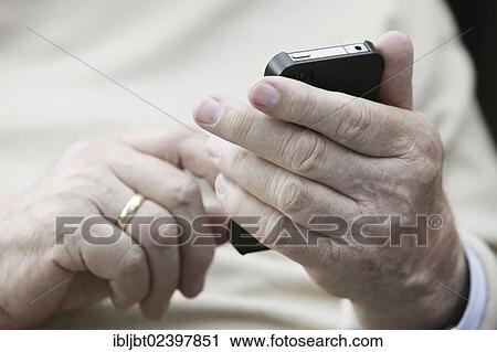 Stock Image - Senior holding a smartphone in his hands. Fotosearch