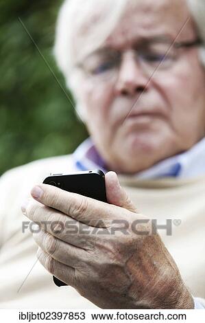 Stock Image - Senior holding a smartphone in his hands. Fotosearch