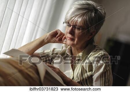 "Senior woman sitting at the window and reading a book, North Rhine-Westphalia, Germany, Europe" View Large Photo Image Stock Image - "Senior woman sitting at the window and reading a book, North Rhine-Westphalia, Germany, Europe". Fotosearch