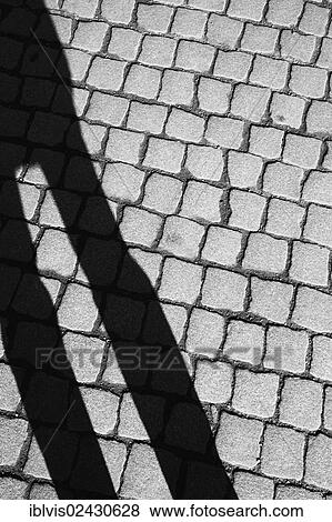 Shadow of a person on cobbled street View Large Photo Image Stock Photo - Shadow of a person on cobbled street. Fotosearch