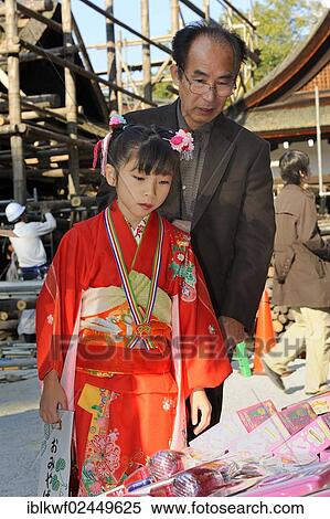 "Shichi-go-san, Seven-Five-Three festival, a father and his daughter in a red kimono who is holding a long bag with candy canes, Chitose-ame, are selecting presents and toys, Kamigamo Jinja, Kyoto, Japan, East Asia, Asia" View Large Photo Image Stock Photography - "Shichi-go-san, Seven-Five-Three festival, a father and his daughter in a red kimono who is holding a long bag with candy canes, Chitose-ame, are selecting presents and toys, Kamigamo Jinja, Kyoto, Japan, East Asia, Asia". Fotosearch