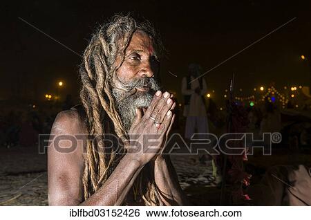 Stock Photograph - "Shiva sadhu, holy man, sitting and praying at night at the Sangam, the confluence of the rivers Ganges, Yamuna and Saraswati, during Kumbha Mela festival, Allahabad, Uttar Pradesh, India, Asia". Fotosearch
