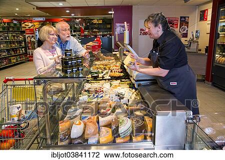 "Shop assistant serving a senior couple at the cheese counter, shopping in a supermarket, Germany, Europe" View Large Photo Image Stock Image - "Shop assistant serving a senior couple at the cheese counter, shopping in a supermarket, Germany, Europe". Fotosearch