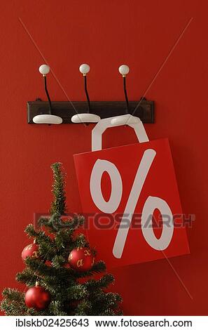 "Shopping bag with per cent sign hanging on nostalgic coat hooks, Christmas tree at front" View Large Photo Image Stock Image - "Shopping bag with per cent sign hanging on nostalgic coat hooks, Christmas tree at front". Fotosearch