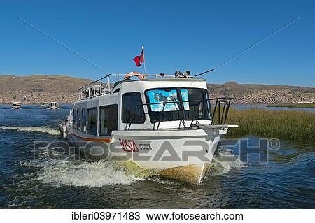 Stock Image - "Sightseeing boat on Lake Titicaca, city of Puno at the back, Puno Region, Peru, South America". Fotosearch