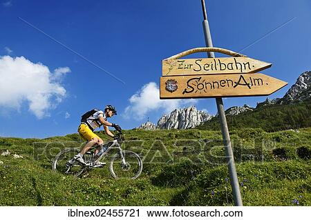 Stock Image - "Signpost, mountain biker on Kampenwand Mountain, Chiemgau, Upper Bavaria, Bavaria, Germany, Europe". Fotosearch