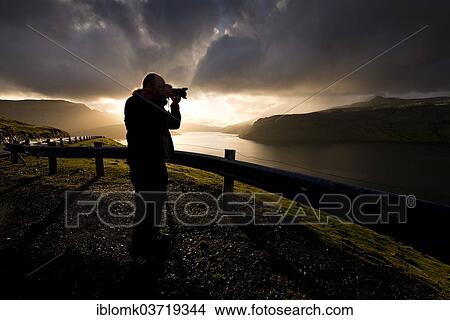 "Silhouette of a photographer standing in front of dramatic, atmospheric clouds, Streymoy, Faroe Islands, Denmark, Europe" View Large Photo Image Picture - "Silhouette of a photographer standing in front of dramatic, atmospheric clouds, Streymoy, Faroe Islands, Denmark, Europe". Fotosearch