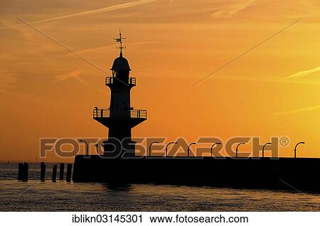 Stock Image - "Silhouette of the Brunsbuettel Mole 1 lighthouse in front of a evening sky, Brunsbuttel, Schleswig-Holstein, Germany, Europe". Fotosearch