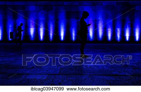 Stock Photo - "Silhouette, woman with mobile phone against blue lighted building, Campus Westend, Goethe University Frankfurt, Frankfurt am Main, Hesse, Germany, Europe". Fotosearch