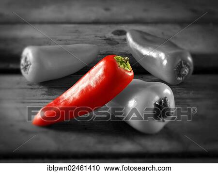 Stock Image - Single red sweet pepper amongst other peppers. Fotosearch
