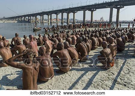Stock Image - "Sitting in silence at the river Ganges as part of the initiation of new sadhus, during Kumbha Mela festival, Allahabad, Uttar Pradesh, India, Asia". Fotosearch