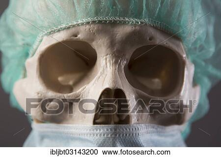 Stock Image - "Skeleton dressed as a doctor with surgical mask and cap, portrait, Germany, Europe". Fotosearch