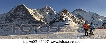 "Skiers in winter, at Mannlichen, with Eiger and Jungfrau mountains behind, Swiss Alps, Switzerland, Europe" View Large Photo Image Stock Photo - "Skiers in winter, at Mannlichen, with Eiger and Jungfrau mountains behind, Swiss Alps, Switzerland, Europe". Fotosearch