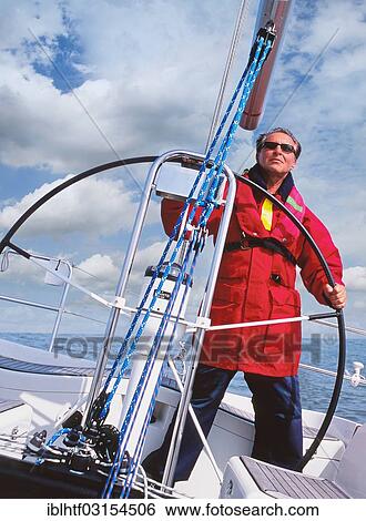 Skipper at the helm of his sailboat View Large Photo Image Stock Photograph - Skipper at the helm of his sailboat. Fotosearch